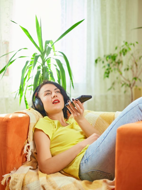 woman-in-hedphones-lying-on-sofa-use-virtual-commands-assistant-on-smartphone.jpg